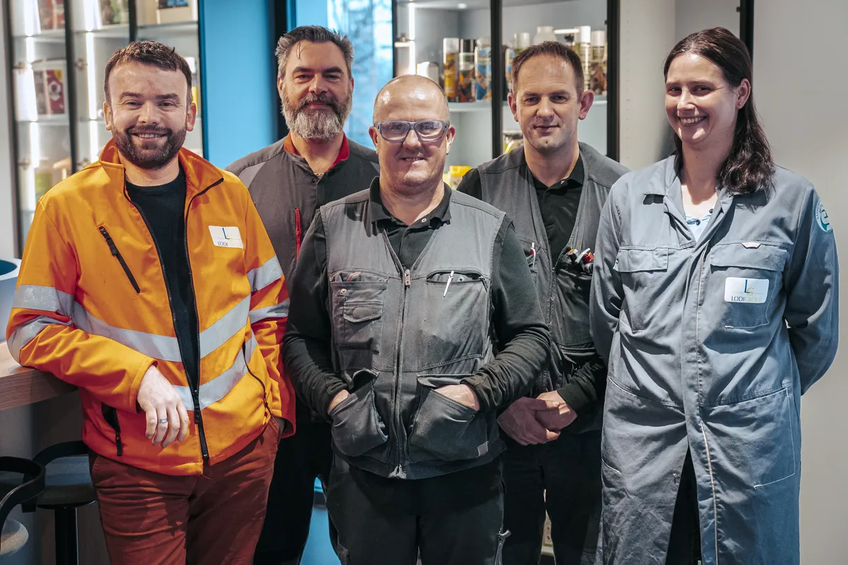 Cinq collaborateurs LODIGROUP souriants dans les locaux de l'entreprise