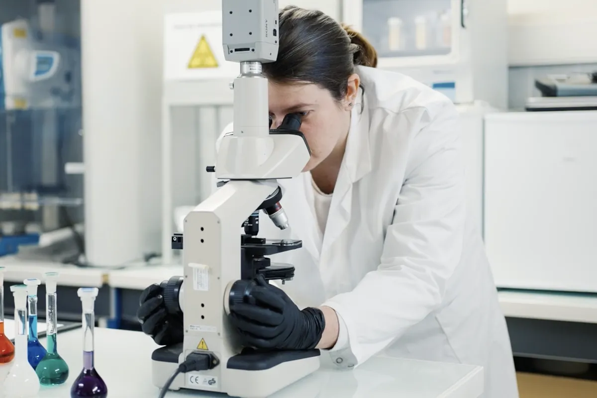 Chercheuse observant un échantillon au microscope dans le laboratoire R&D